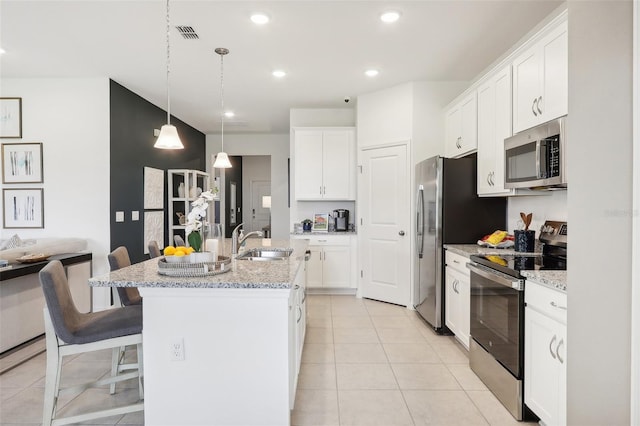 1275 Normandy Dr, Haines City, FL 33844 - kitchen with stainless steel appliances, white cabinetry, a center island with sink, a breakfast bar area, and recessed lighting