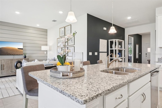 1275 Normandy Dr, Haines City, FL 33844 - kitchen with dishwasher, an island with sink, white cabinetry, decorative light fixtures, and light stone counters