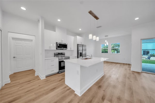 9333 Hialeah Ter, Port Charlotte, FL 33981 - kitchen featuring appliances with stainless steel finishes, white cabinets, a center island with sink, light wood finished floors, and recessed lighting