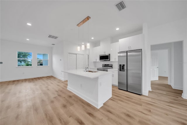9333 Hialeah Ter, Port Charlotte, FL 33981 - kitchen featuring appliances with stainless steel finishes, white cabinetry, light countertops, light wood-type flooring, and a kitchen island with sink
