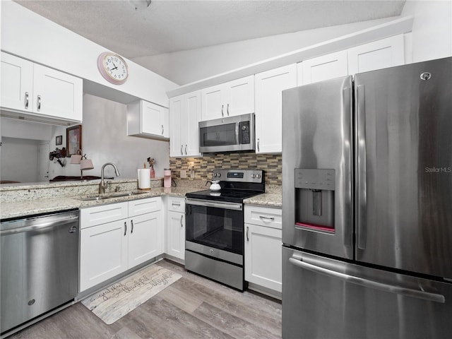 5421 Lake Margaret Dr Unit 178, Orlando, FL 32812 - kitchen with stainless steel appliances, vaulted ceiling, light wood finished floors, white cabinets, and backsplash