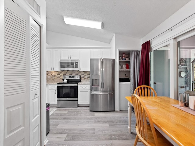 5421 Lake Margaret Dr Unit 178, Orlando, FL 32812 - kitchen featuring appliances with stainless steel finishes, lofted ceiling, white cabinets, light wood finished floors, and decorative backsplash