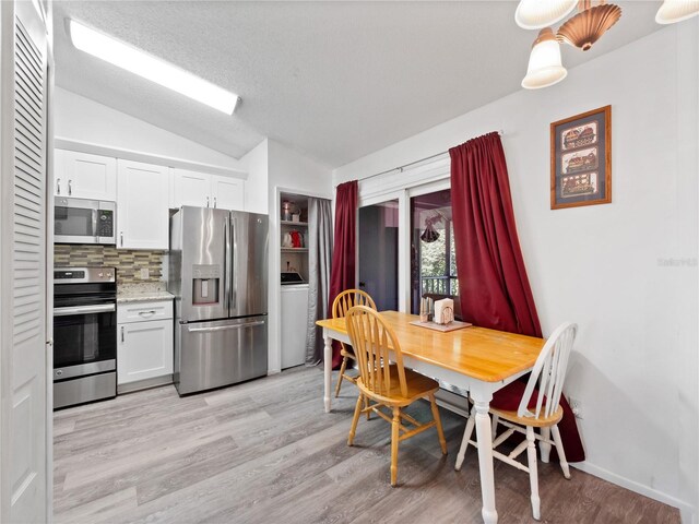5421 Lake Margaret Dr Unit 178, Orlando, FL 32812 - dining room featuring lofted ceiling, light wood-type flooring, and washer / clothes dryer