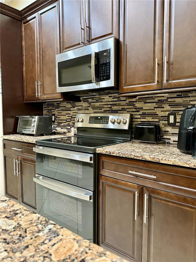 1945 Torrey Dr, Orlando, FL 32818 - kitchen featuring appliances with stainless steel finishes, tasteful backsplash, dark brown cabinetry, and light stone countertops