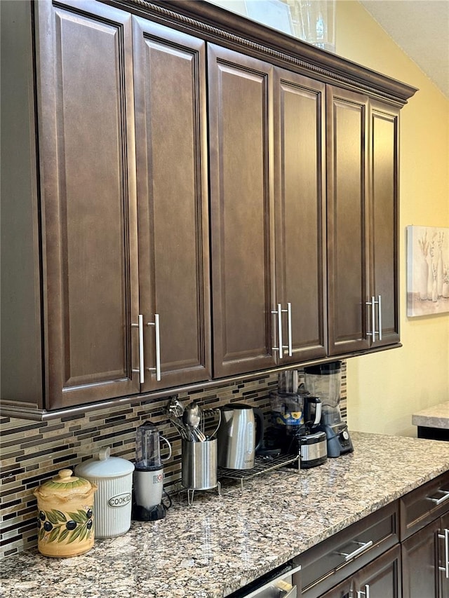 1945 Torrey Dr, Orlando, FL 32818 - kitchen with decorative backsplash, dark brown cabinets, and light stone countertops