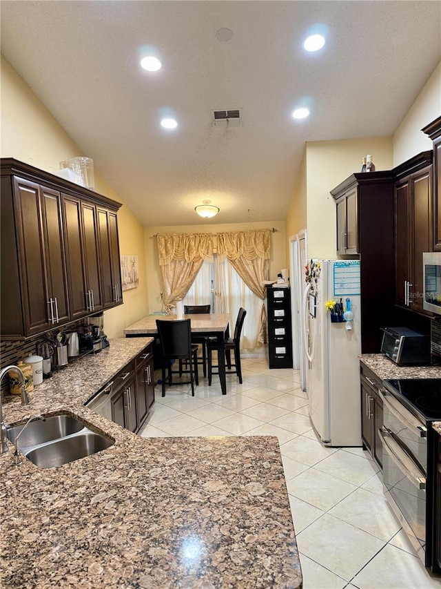 1945 Torrey Dr, Orlando, FL 32818 - kitchen featuring stainless steel appliances, dark brown cabinetry, dark stone counters, recessed lighting, and light tile patterned floors
