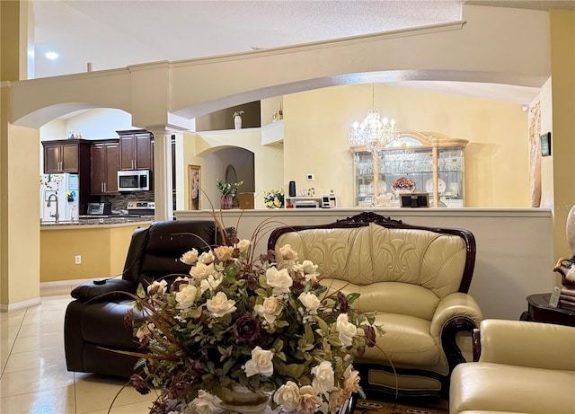 1945 Torrey Dr, Orlando, FL 32818 - living room featuring light tile patterned floors, a chandelier, arched walkways, and decorative columns