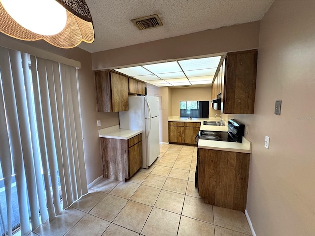 5359 Vineland Rd Unit S, Orlando, FL 32811 - kitchen with freestanding refrigerator, light countertops, light tile patterned floors, brown cabinets, and black electric range
