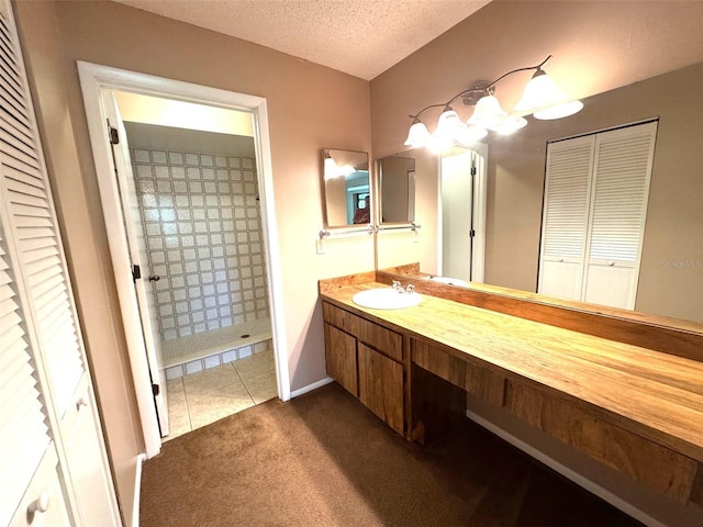 5359 Vineland Rd Unit S, Orlando, FL 32811 - full bathroom featuring a closet, vanity, tiled shower, a textured ceiling, and tile patterned flooring