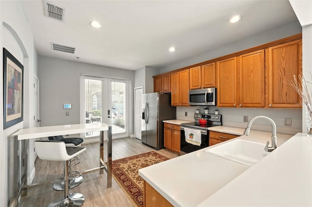 14241 Confetti Dr, Windermere, FL 34786 - kitchen featuring appliances with stainless steel finishes, french doors, brown cabinets, recessed lighting, and light wood finished floors