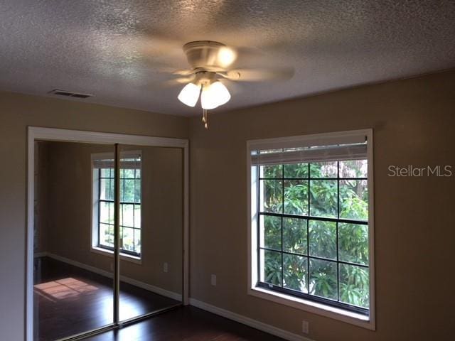 3370 Cedar Springs Pl Unit 156, Winter Park, FL 32792 - unfurnished bedroom with a textured ceiling, a closet, a ceiling fan, and dark wood-style flooring