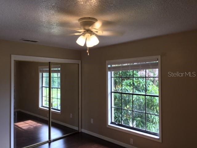 3370 Cedar Springs Pl Unit 156, Winter Park, FL 32792 - unfurnished bedroom with a textured ceiling, multiple windows, dark wood-style floors, a closet, and ceiling fan