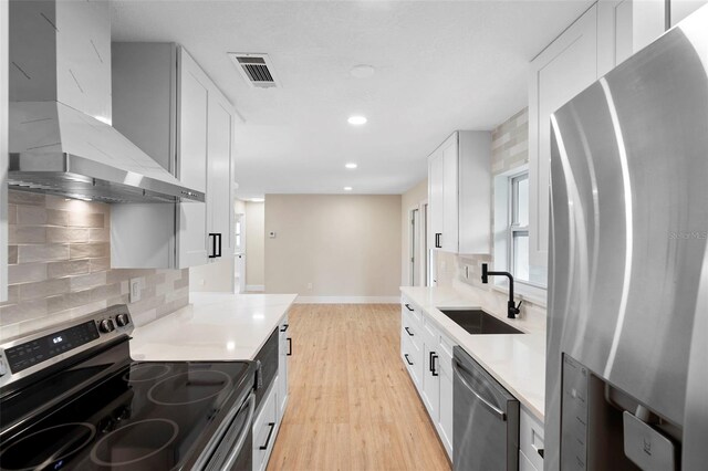 5310 Pineview Way, Apopka, FL 32703 - kitchen featuring stainless steel appliances, wall chimney exhaust hood, light wood-style flooring, backsplash, and white cabinetry