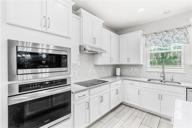9518 Bolero Rd, Winter Garden, FL 34787 - kitchen featuring appliances with stainless steel finishes, under cabinet range hood, light countertops, white cabinets, and decorative backsplash