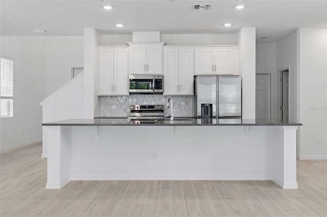 1198 Happy Forest Loop, Deland, FL 32720 - kitchen featuring appliances with stainless steel finishes, backsplash, white cabinets, light wood finished floors, and recessed lighting