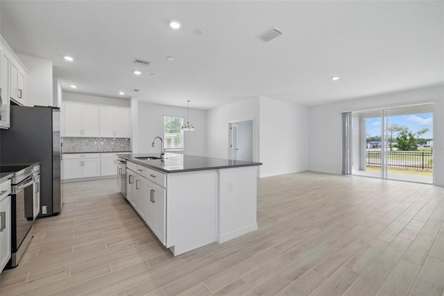 1198 Happy Forest Loop, Deland, FL 32720 - kitchen with dark countertops, stainless steel appliances, light wood-style flooring, tasteful backsplash, and recessed lighting