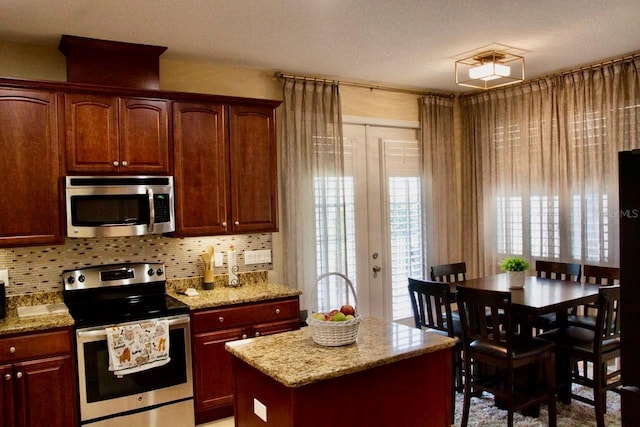 2851 Swoop Cir, Kissimmee, FL 34741 - kitchen featuring appliances with stainless steel finishes, light stone counters, backsplash, and a center island