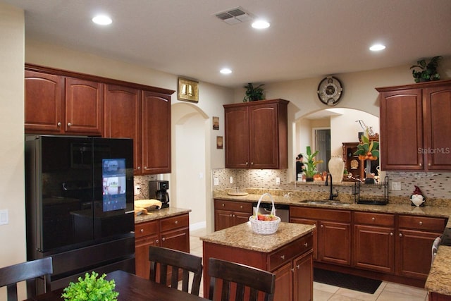 2851 Swoop Cir, Kissimmee, FL 34741 - kitchen with fridge, arched walkways, decorative backsplash, light tile patterned floors, and light stone countertops