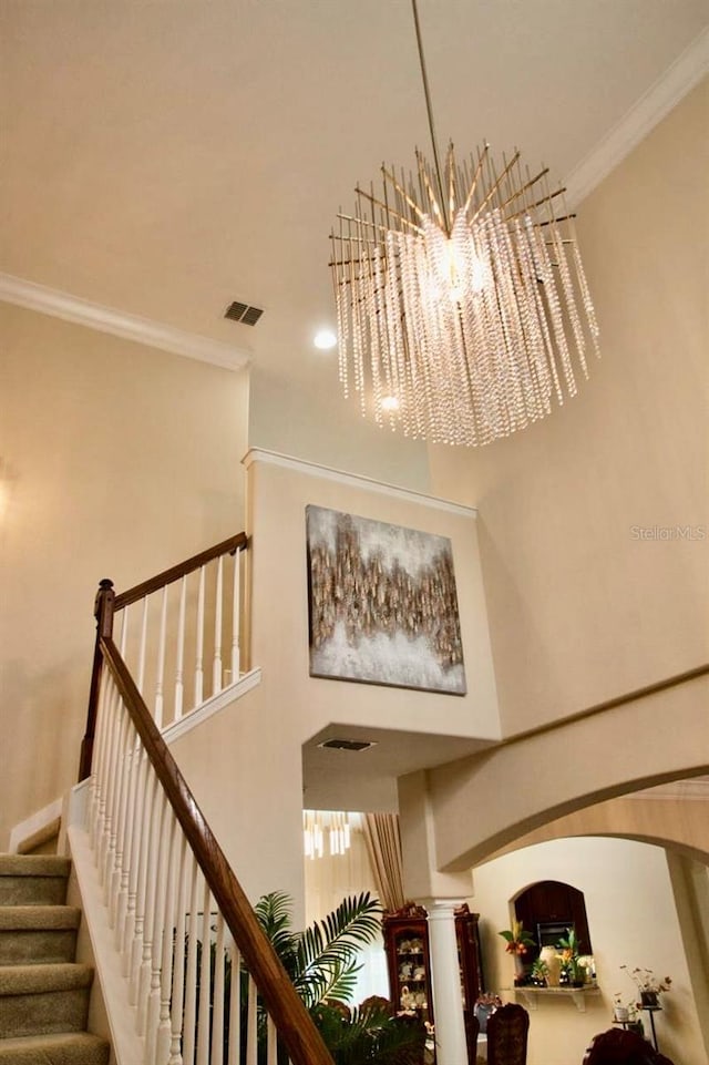 2851 Swoop Cir, Kissimmee, FL 34741 - stairway featuring a high ceiling, arched walkways, and crown molding