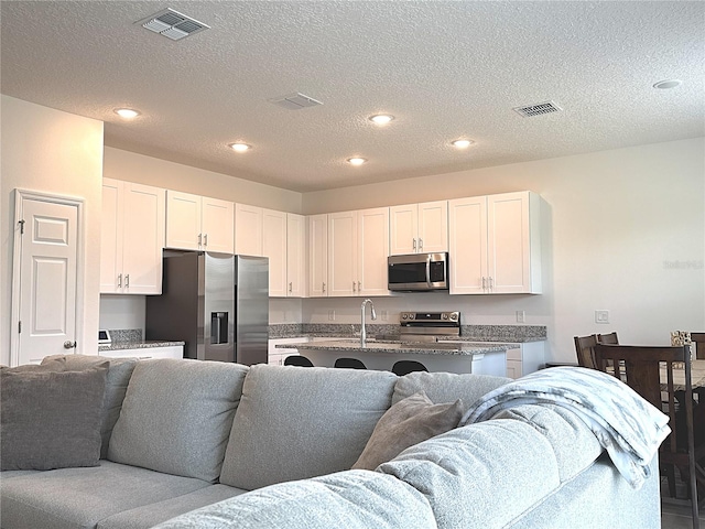 764 Richmond Estate Ave, Haines City, FL 33844 - kitchen with stainless steel appliances, open floor plan, white cabinets, recessed lighting, and a textured ceiling