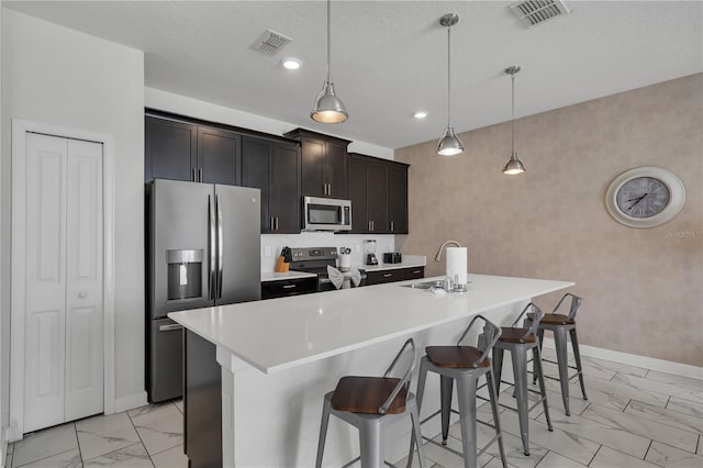 9005 Stinger Dr, Davenport, FL 33896 - kitchen with appliances with stainless steel finishes, light marble finish flooring, a kitchen island with sink, a breakfast bar area, and light countertops