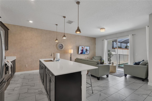 9005 Stinger Dr, Davenport, FL 33896 - kitchen with open floor plan, light marble finish floors, light countertops, a breakfast bar area, and a kitchen island with sink