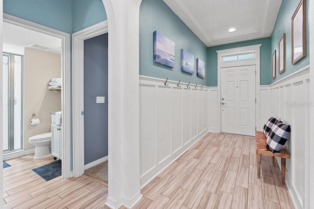 1210 Woods Landing Dr, Minneola, FL 34715 - mudroom with wood finish floors, a wainscoted wall, a textured ceiling, a decorative wall, and arched walkways