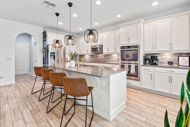 1210 Woods Landing Dr, Minneola, FL 34715 - kitchen with stainless steel appliances, backsplash, a breakfast bar area, arched walkways, and recessed lighting