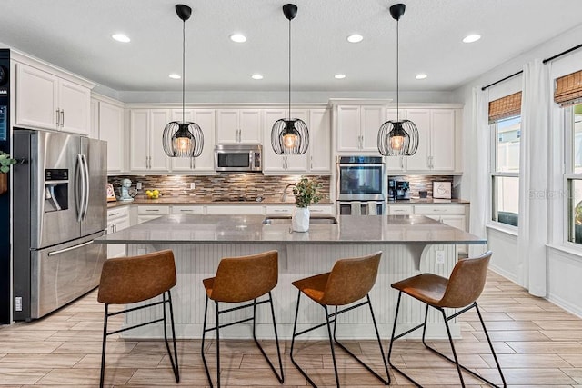 1210 Woods Landing Dr, Minneola, FL 34715 - kitchen featuring appliances with stainless steel finishes, backsplash, white cabinets, a breakfast bar area, and recessed lighting