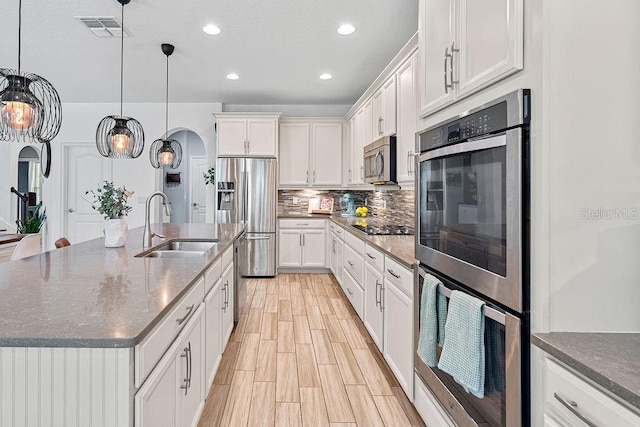 1210 Woods Landing Dr, Minneola, FL 34715 - kitchen with appliances with stainless steel finishes, arched walkways, recessed lighting, decorative backsplash, and dark stone countertops