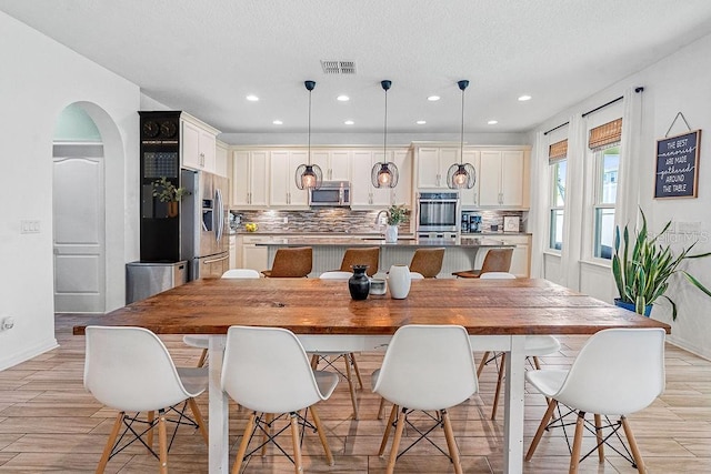 1210 Woods Landing Dr, Minneola, FL 34715 - dining room with arched walkways, light wood-style floors, recessed lighting, and a textured ceiling