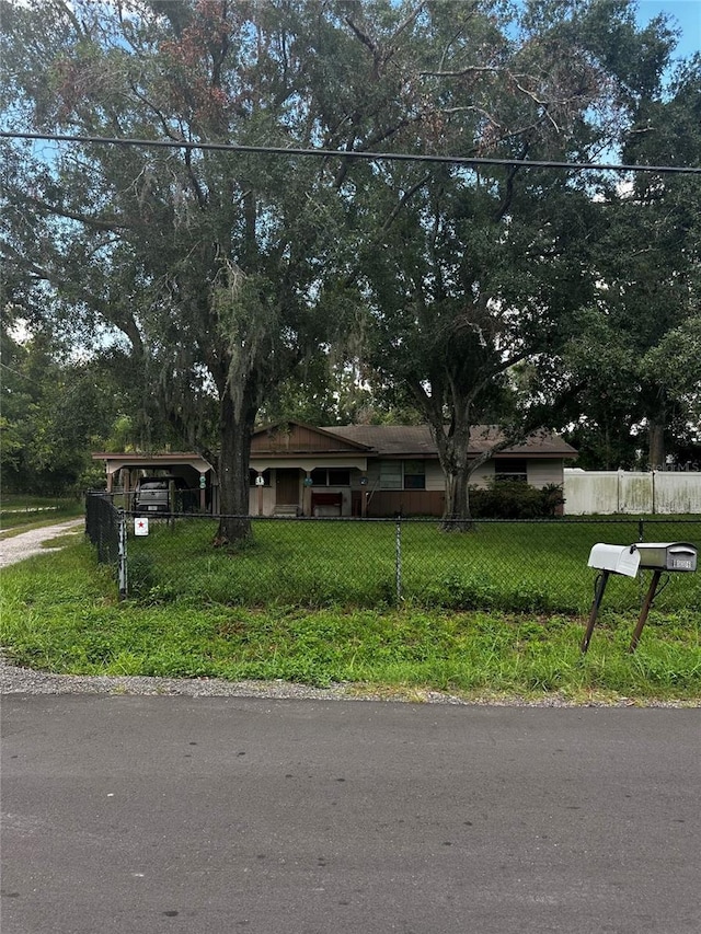 10004 Vaughn St, Gibsonton, FL 33534 - view of front of property with a detached carport, a fenced front yard, and driveway
