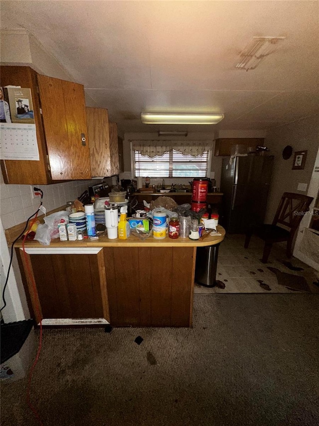 10004 Vaughn St, Gibsonton, FL 33534 - kitchen featuring freestanding refrigerator, brown cabinetry, a peninsula, carpet, and light countertops