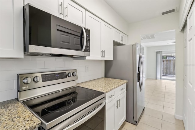 2200 S Palmetto Ave Unit B050, South Daytona, FL 32119 - kitchen featuring stainless steel appliances, white cabinets, light tile patterned flooring, and tasteful backsplash