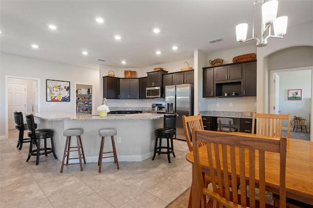 416 Riders Loop, Auburndale, FL 33823 - kitchen featuring appliances with stainless steel finishes, dark brown cabinetry, a large island with sink, recessed lighting, and light stone countertops