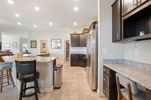 416 Riders Loop, Auburndale, FL 33823 - kitchen featuring stainless steel fridge with ice dispenser, dark brown cabinetry, a kitchen bar, recessed lighting, and light stone counters