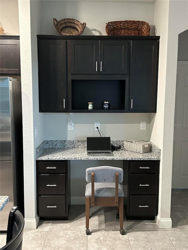 416 Riders Loop, Auburndale, FL 33823 - kitchen with high end fridge, light tile patterned floors, a textured wall, light stone counters, and built in study area