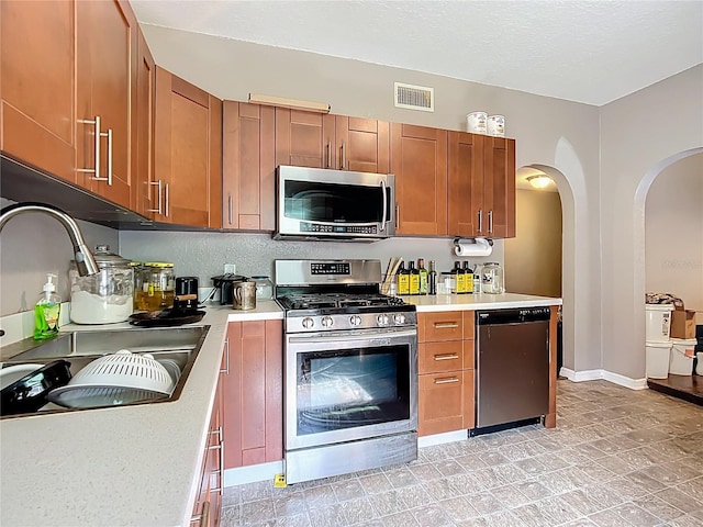 1505 E Elm Rd, Lakeland, FL 33801 - kitchen with appliances with stainless steel finishes, light countertops, arched walkways, and brown cabinets