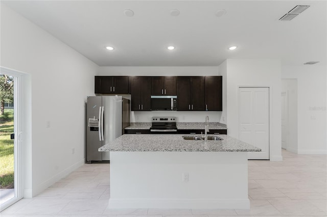 627 W Glenhaven Dr, Citrus Springs, FL 34434 - kitchen featuring stainless steel appliances, a center island with sink, light stone countertops, recessed lighting, and dark brown cabinets