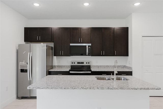 627 W Glenhaven Dr, Citrus Springs, FL 34434 - kitchen with appliances with stainless steel finishes, a center island with sink, recessed lighting, dark brown cabinetry, and light stone countertops