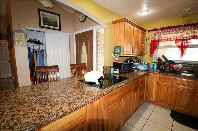 317 Cortez Ct, Kissimmee, FL 34758 - kitchen with black appliances, arched walkways, dark stone countertops, brown cabinets, and light tile patterned floors