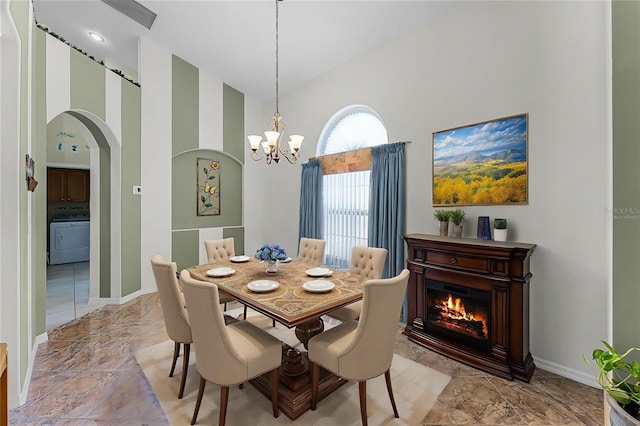 12617 Douglas Fir Ct, Clermont, FL 34711 - dining area featuring washer / dryer, a high ceiling, arched walkways, a chandelier, and a glass covered fireplace