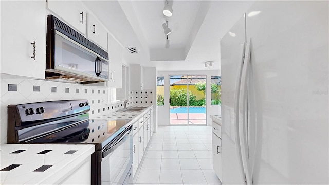 5045 Bermuda Cir Unit 12, Orlando, FL 32808 - kitchen featuring stainless steel range with electric stovetop, freestanding refrigerator, white cabinets, and decorative backsplash