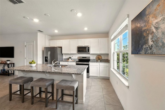 13298 Pontoon Rd, Winter Garden, FL 34787 - kitchen with stainless steel appliances, white cabinetry, light stone countertops, light tile patterned floors, and a breakfast bar area