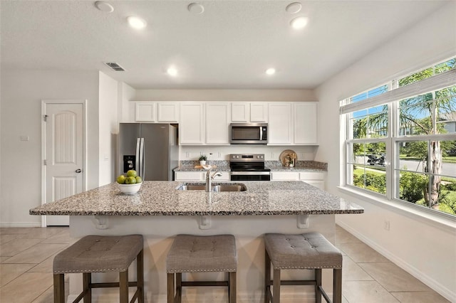 13298 Pontoon Rd, Winter Garden, FL 34787 - kitchen with appliances with stainless steel finishes, light tile patterned flooring, a kitchen bar, white cabinetry, and recessed lighting