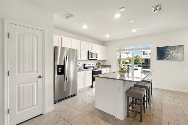 13298 Pontoon Rd, Winter Garden, FL 34787 - kitchen featuring stainless steel appliances, light tile patterned floors, a kitchen breakfast bar, white cabinets, and recessed lighting