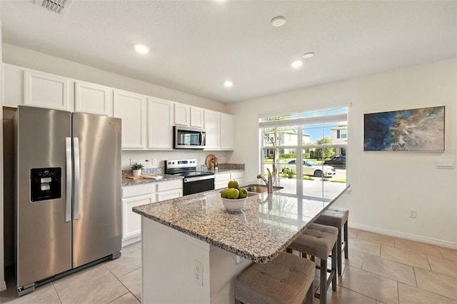 13298 Pontoon Rd, Winter Garden, FL 34787 - kitchen featuring stainless steel appliances, white cabinets, light stone countertops, a kitchen bar, and recessed lighting