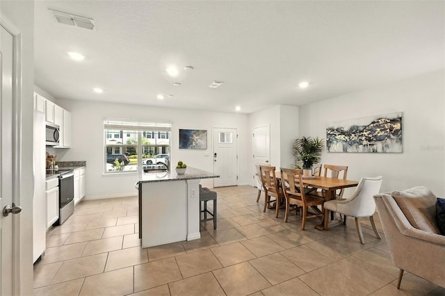 13298 Pontoon Rd, Winter Garden, FL 34787 - kitchen featuring appliances with stainless steel finishes, a kitchen breakfast bar, stone counters, white cabinetry, and a kitchen island with sink