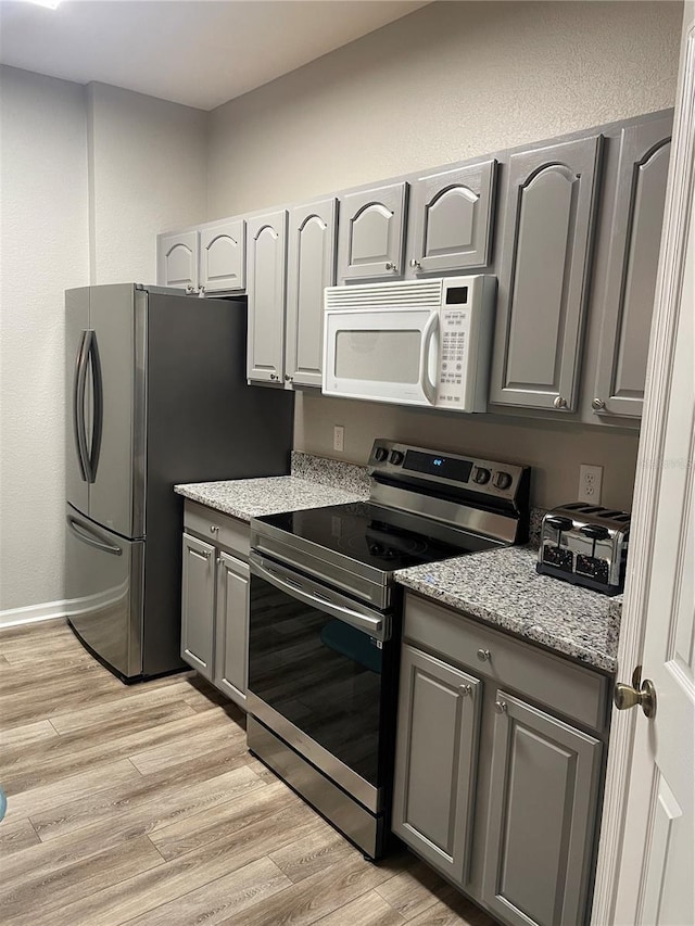 2817 Almaton Loop Unit 403, Kissimmee, FL 34747 - kitchen with stainless steel appliances, gray cabinetry, light wood-style floors, and light stone countertops