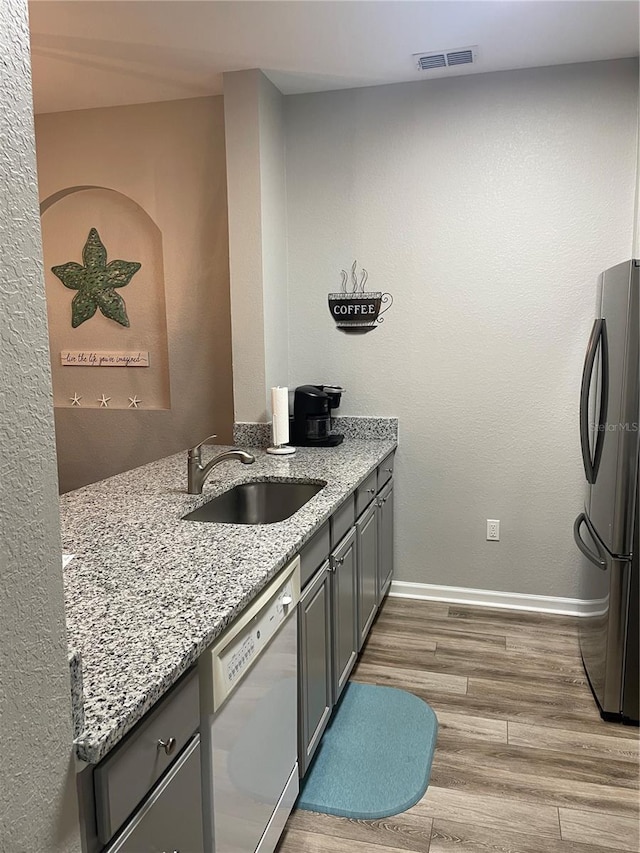 2817 Almaton Loop Unit 403, Kissimmee, FL 34747 - kitchen featuring dishwasher, freestanding refrigerator, gray cabinetry, wood finished floors, and light stone counters